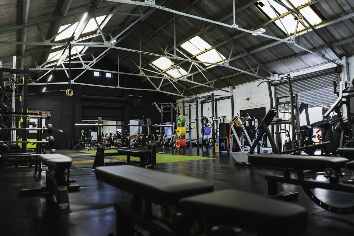 Spacious industrial gym floor with benches, racks and free weights
