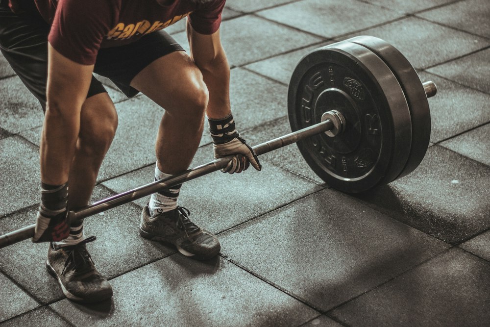 Lifter pulling a loaded barbell deadlift from a rubber gym floor